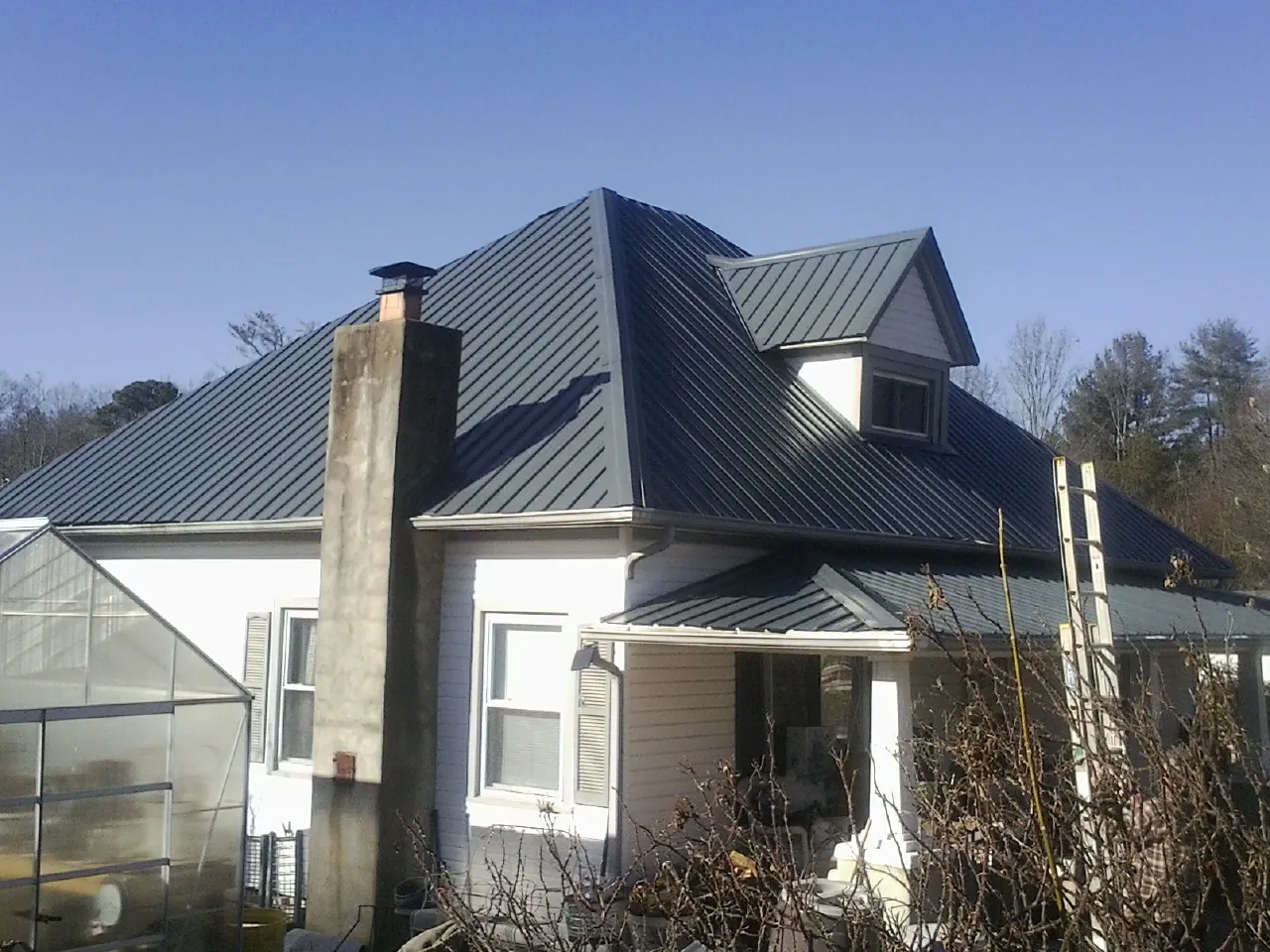 Dark blue standing seam metal roof on a white farmhouse with dormer — Slate & Tile Roof Repair by Roofing Brothers in Tullahoma