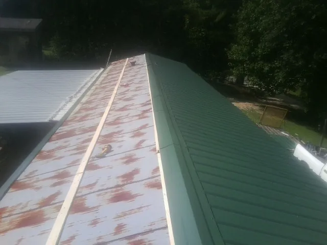 Old rusted panels beside newly installed green metal roofing — Wind Damage Roof Repair by Roofing Brothers in Tullahoma
