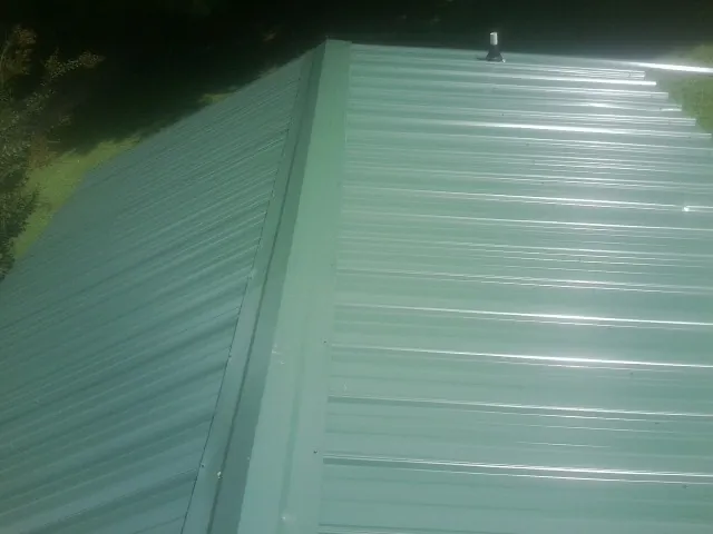 New green metal panels meeting at the ridge of a roof — Flat Roof Repair work by our crew in Tullahoma