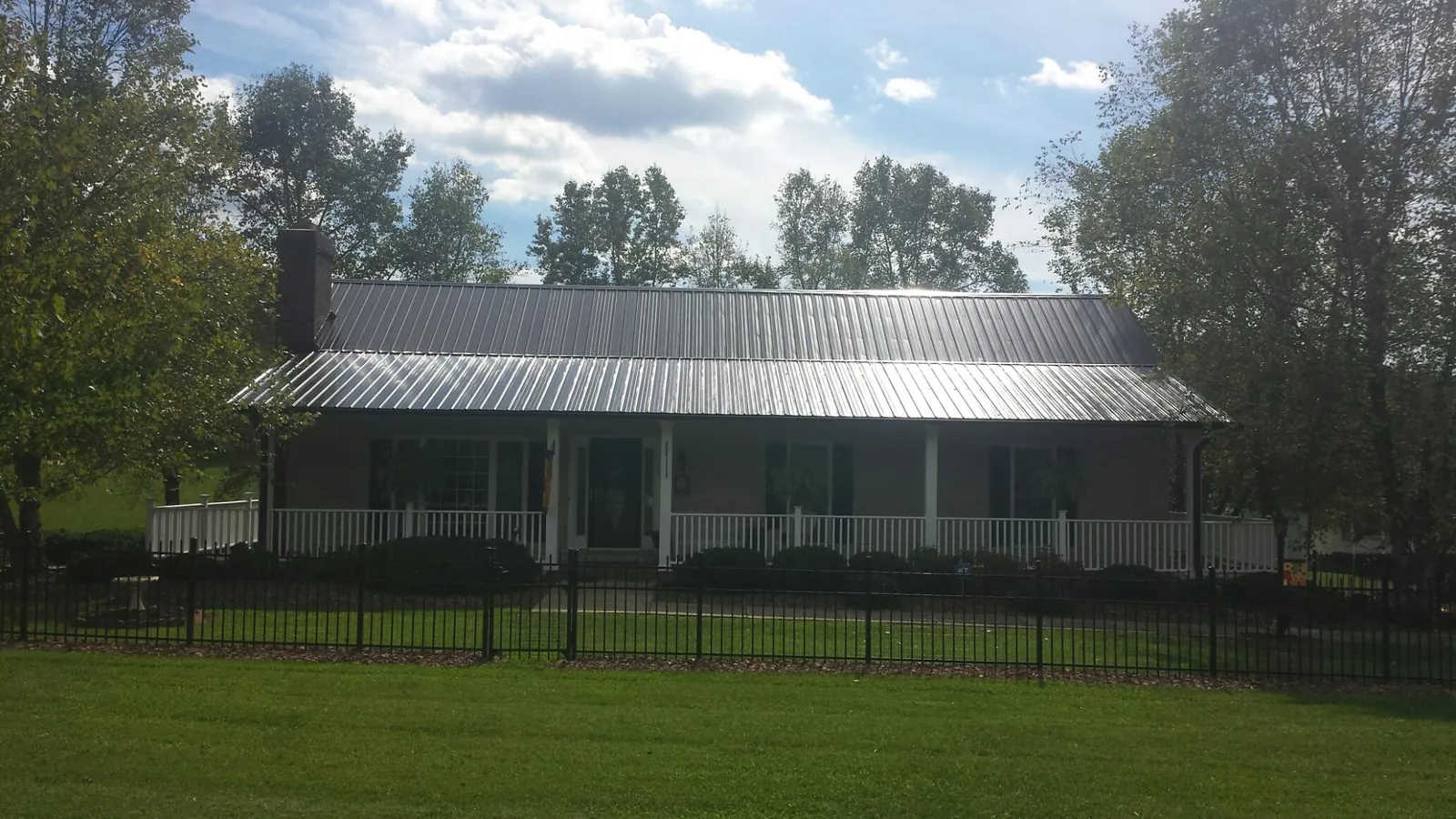 Gray metal roof on a brick ranch with a full width front porch — Gutter Guard Installation work by our crew in Tullahoma