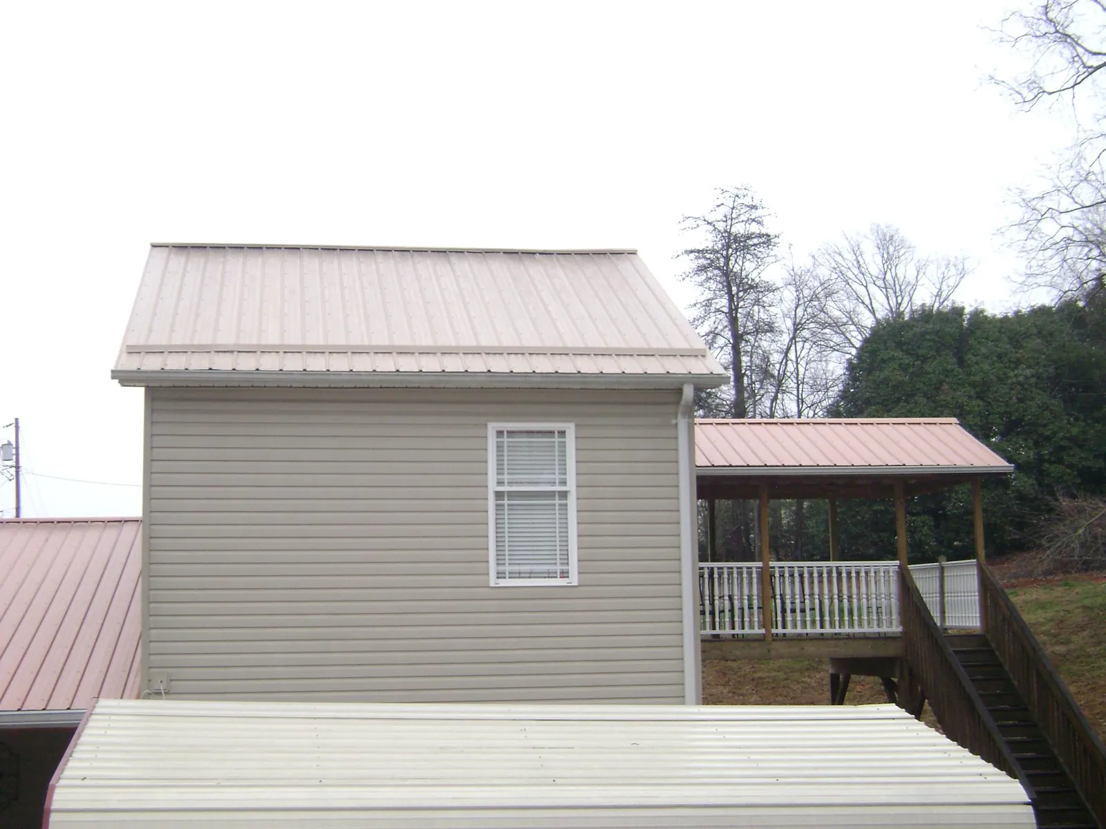 Tan metal roofs on a two story addition and attached porch, from a Roof Replacement job in Tullahoma