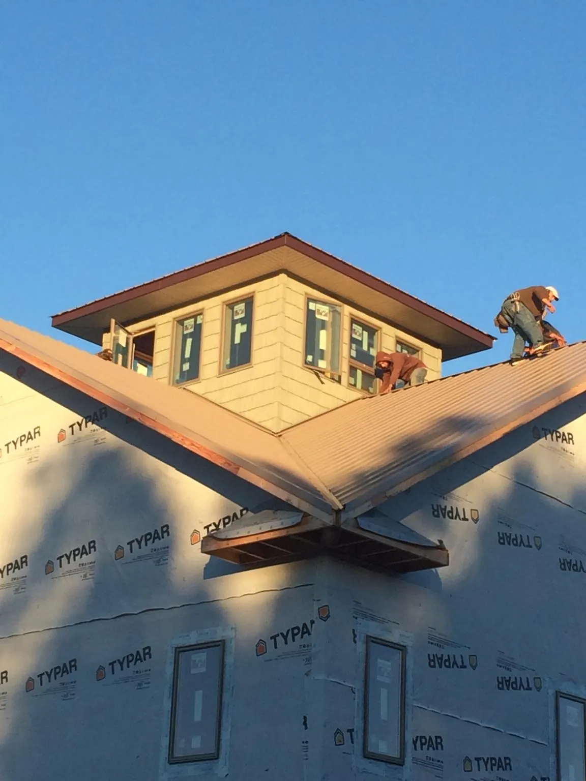 Roofers working around a rooftop cupola on a new metal roof at sunset — Roof Waterproofing in Tullahoma by Roofing Brothers